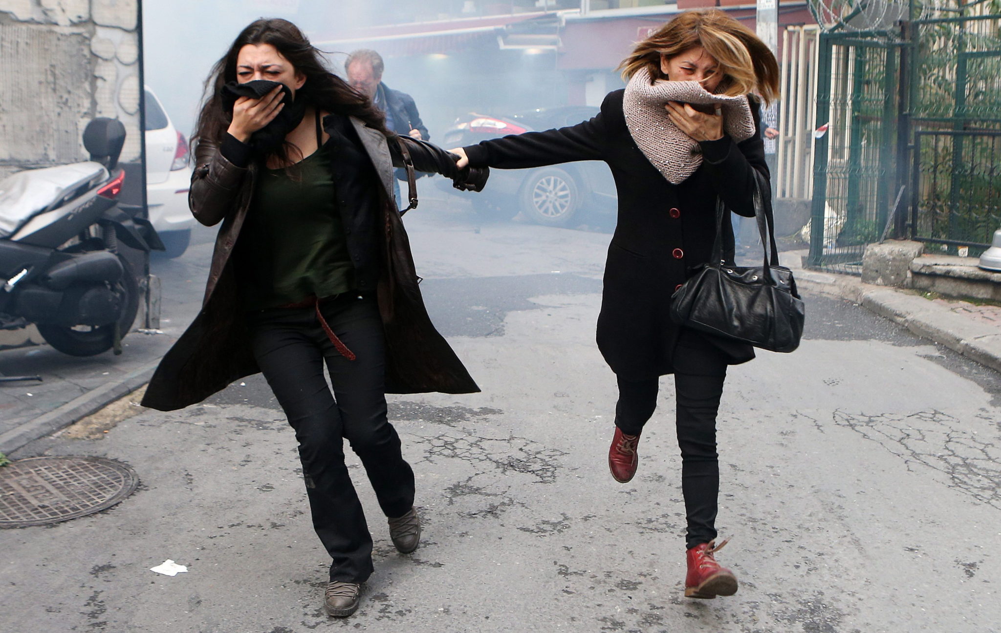 Dwie kobiety biorące udział w manifestacji przeciwko aresztowaniu liderów Ludowej Partii Demokratycznej (HDP) uciekają po tym, jak turecka policja użyła gazu przeciwko protestującemu tłumowi. Istambuł, Turcja, 5 listopada 2016