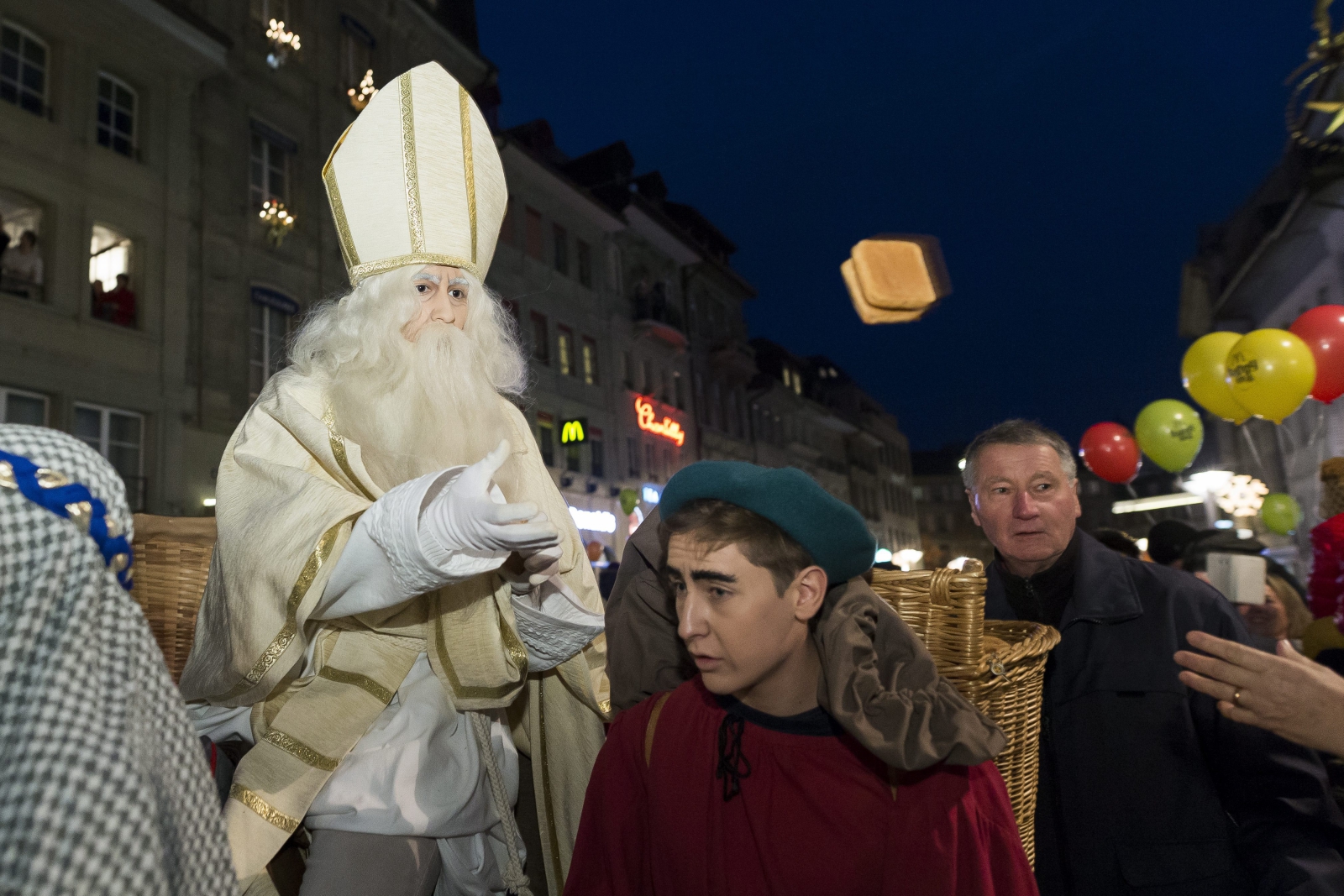 Mężczyzna przebrany za świętego Mikołaja jedzie na osiołku i rozdaje prezenty w czasie procesji ku czci św. Mikołaja we Friburgu, Szwajcaria.