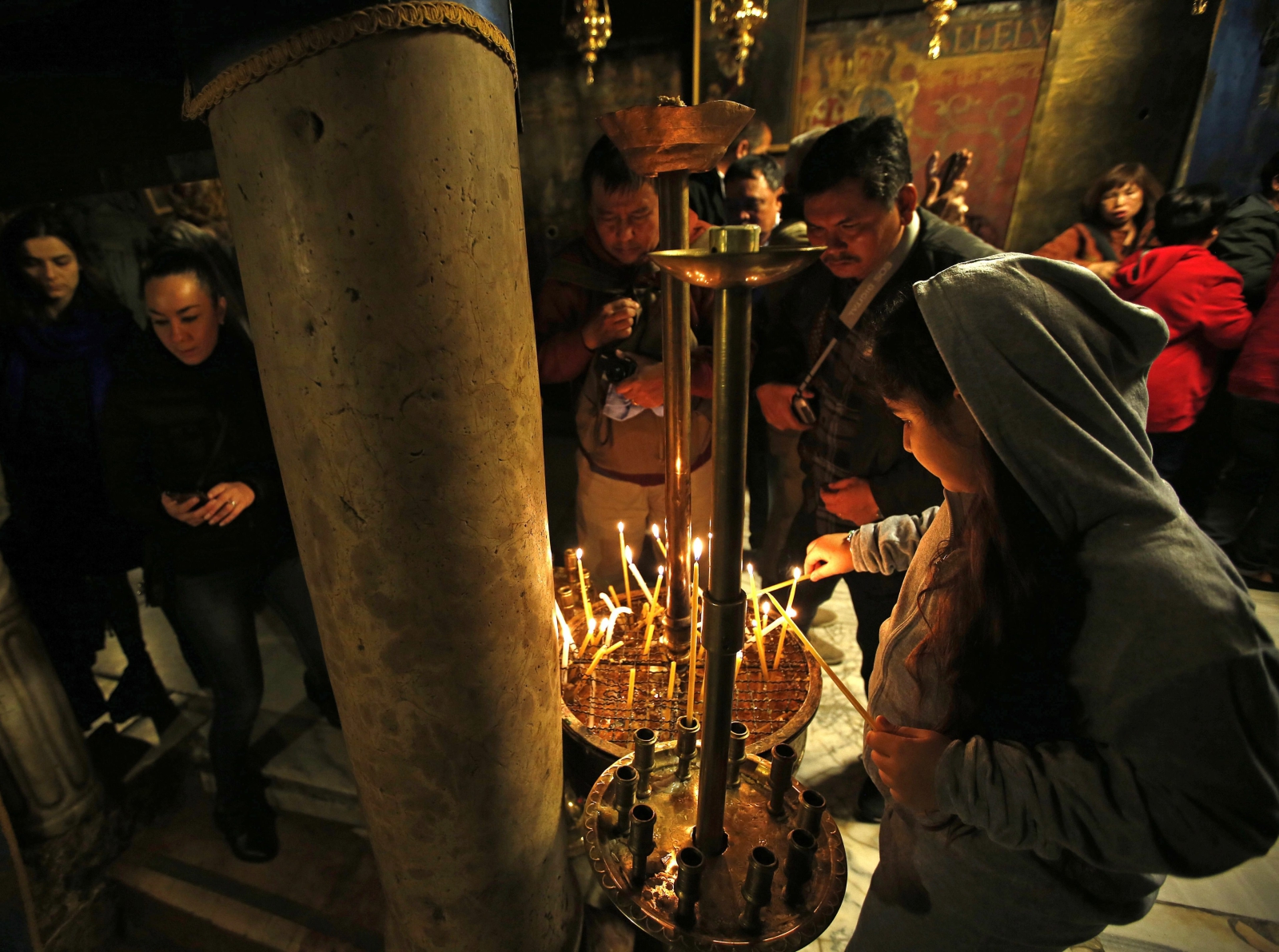 Pielgrzymi zapalają świece w Kościele Bożego Narodzenia w Betlejem. Kościół ten, jeden z najstarszych na świecie jest ciągle w remoncie, cały pokryty plastikiem i folią.