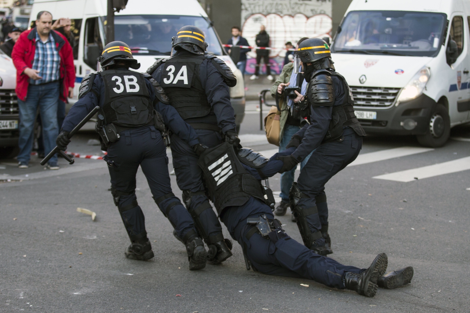 Nieprzytomny policjant odciągany przez swoich kolegów po tym jak otrzymał cios kamieniem w głowę w trakcie zamieszek w Paryżu.