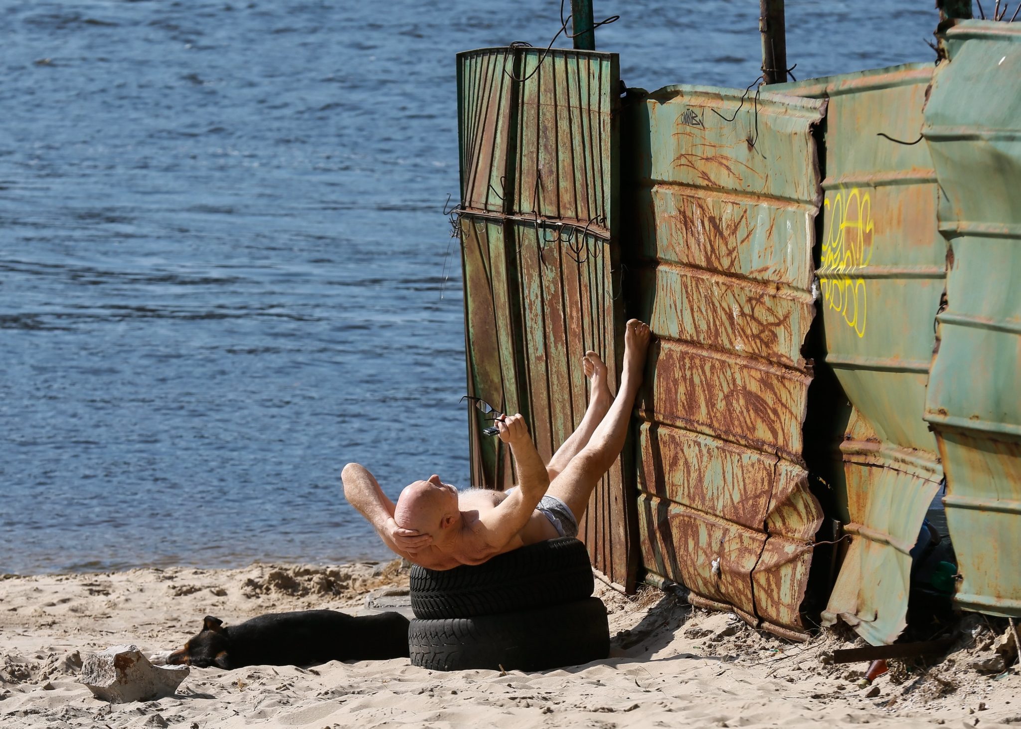 Ukraina: opalający się mężczyzna nad brzegiem rzeki Dniepr w Kijowie (foto. PAP/EPA/SERGEY DOLZHENKO)