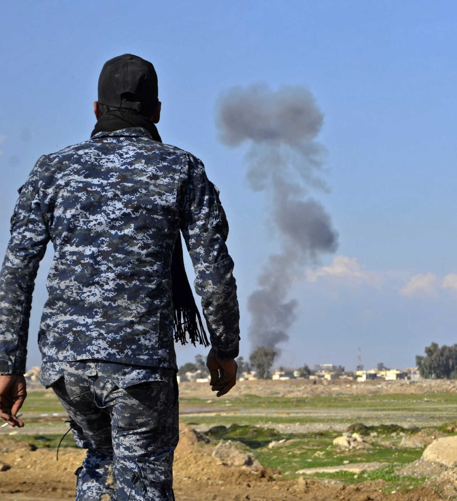 Irakijski policjant patrzy na dym z samochodu-pułapki w zachodniej części Mosulu.