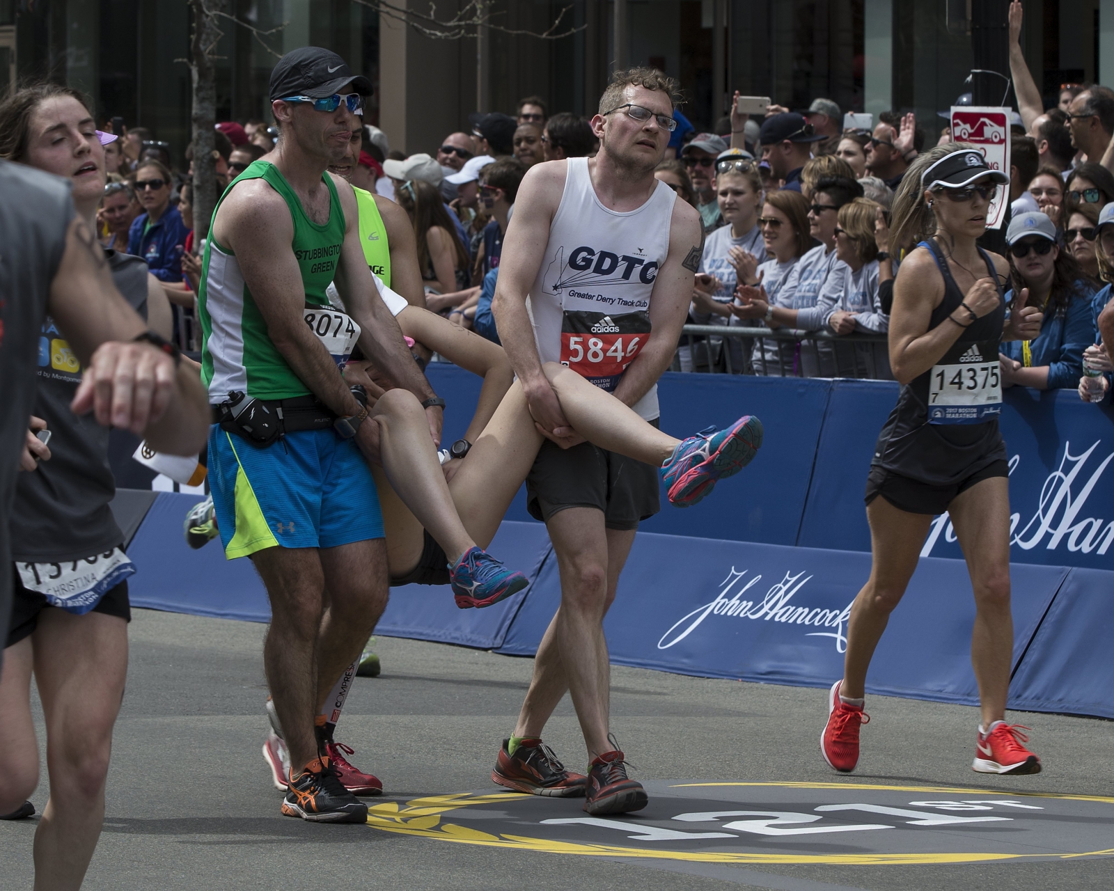Uczestnicy pomagają innym w przekroczeniu linii mety 121 bostońskiego maratonu w Boston, Ma