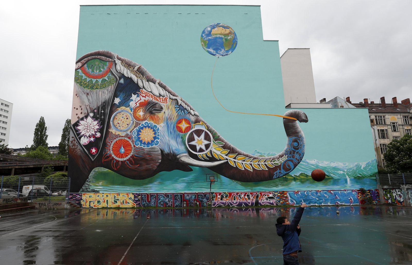 Chłopiec bawi się naprzeciwko ogromnego graffiti przedstawiającego słonia, Berlin, Niemcy.