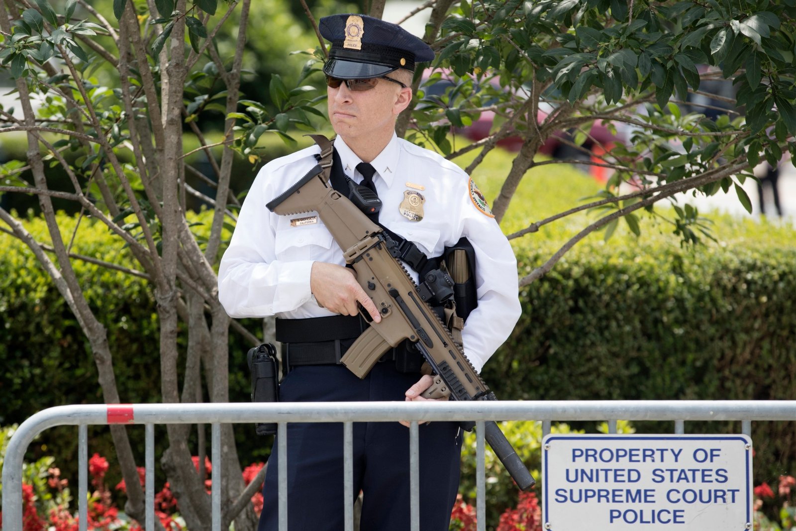 Policjant pełniący rolę strażnika stoi z bronią przez budynkiem Sądu Najwyższego, USA.