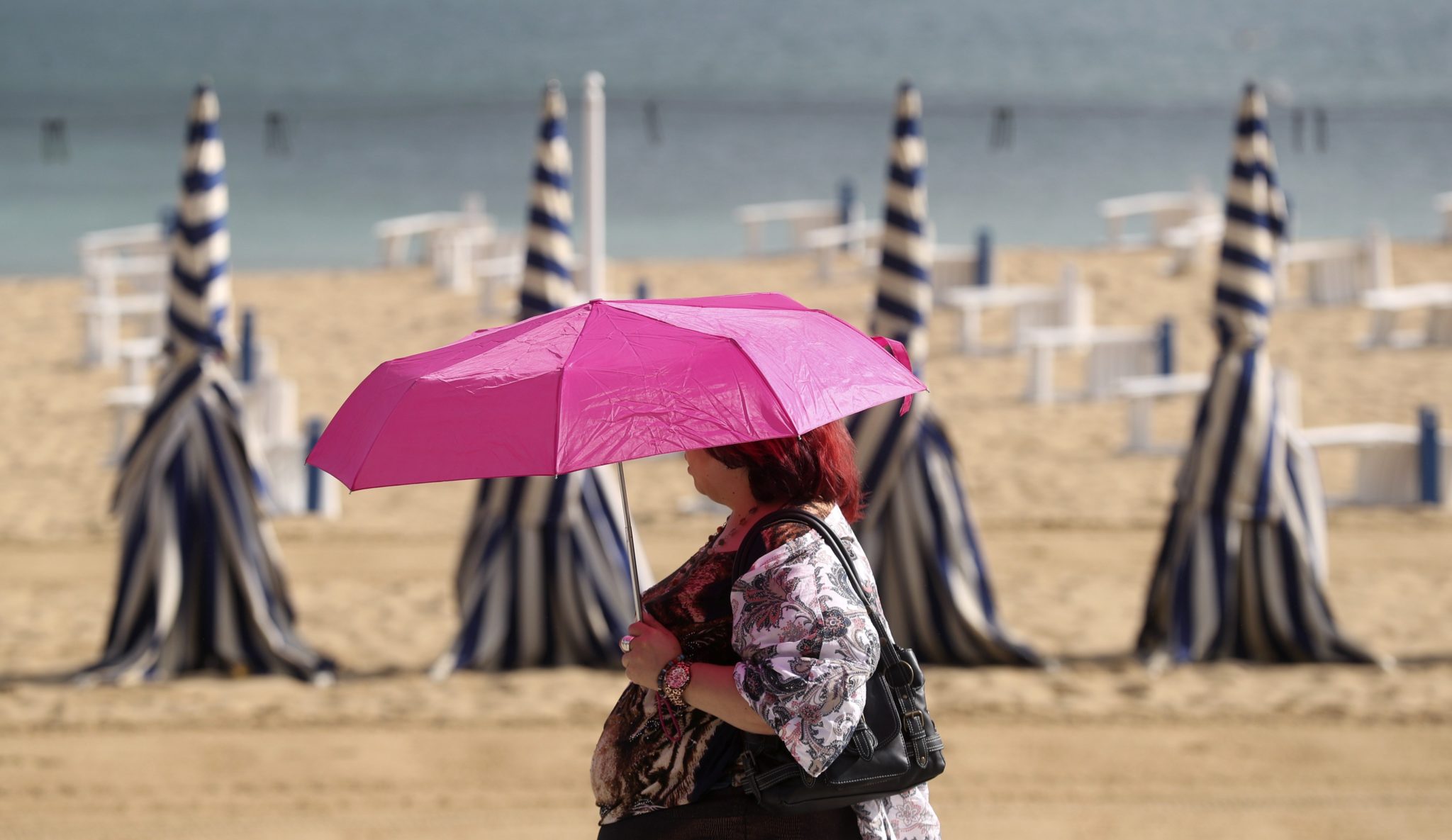 Kobieta z parasolką w czasie upałów na plaży Ondaretta w San San Sebastian, w północnej Hiszpanii , fot: Juan Herrero PAP/EPA.