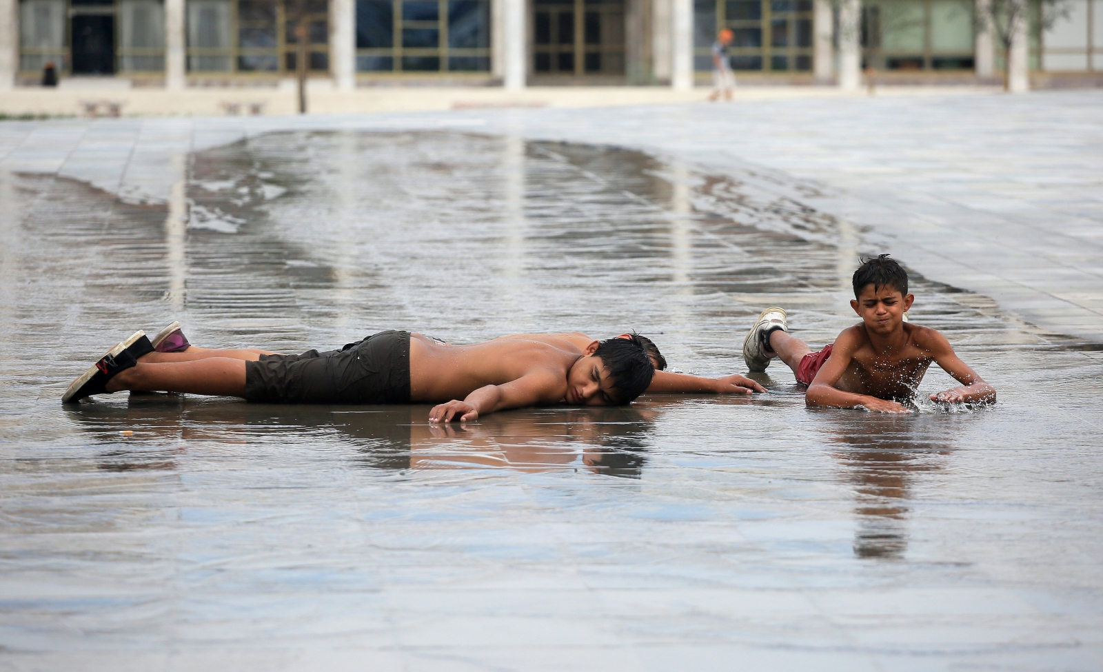 Albańskie dzieci szukają ochłody w czasie upału przy fontannie na głównym placu w Tiranie, Albania,EPA/MALTON DIBRA 
