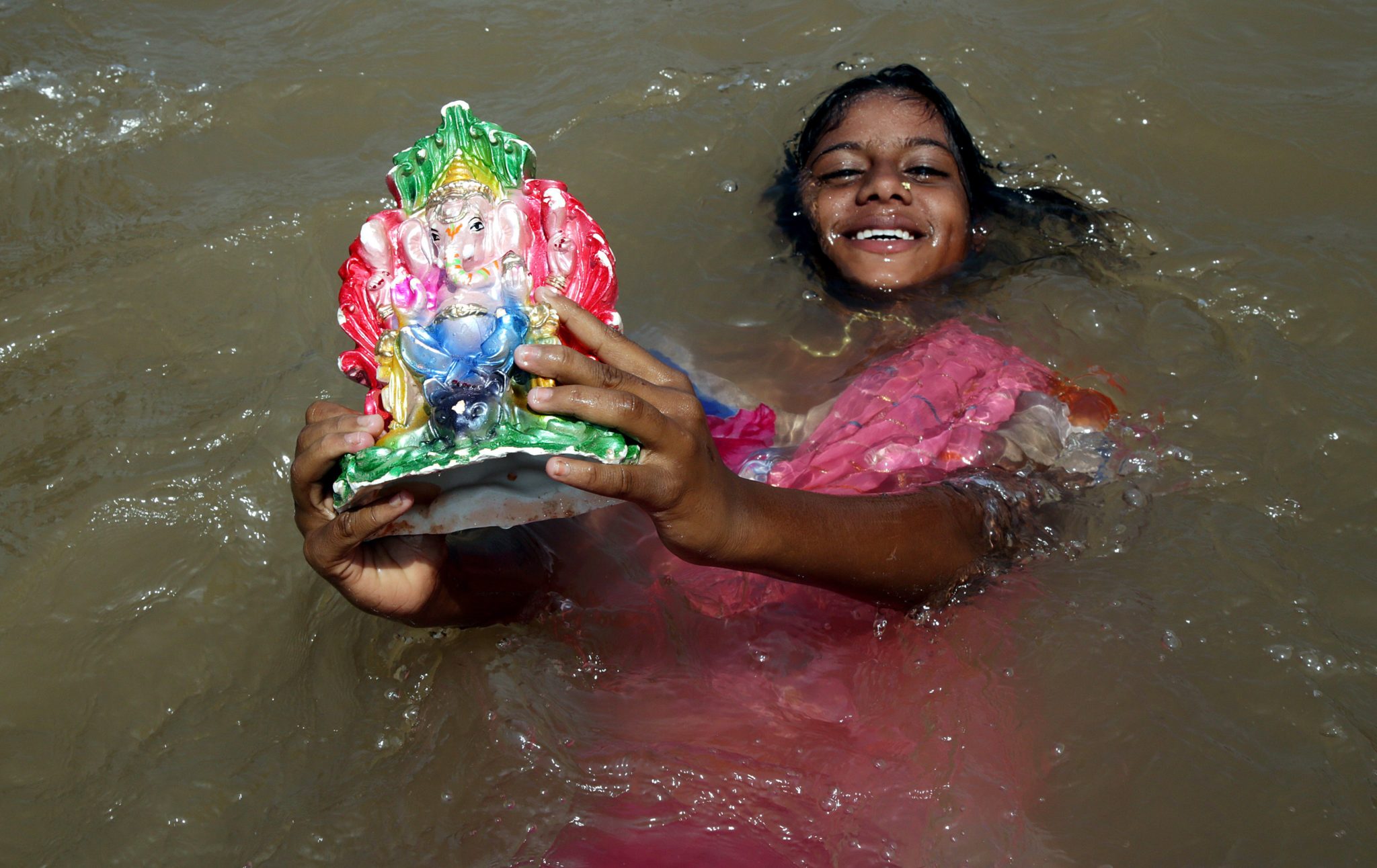 Dziewczynka w rzece Tawi, w ręce trzyma hinduskiego bożka. Trwa festiwal Gangesu, fot: Jaipal Singhm PAP / EPA.
