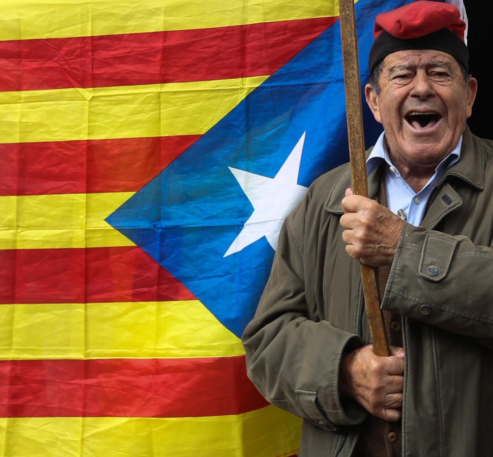 Mężczyzna stoi z flagą Katalonii, Barcelona, Hiszpania.