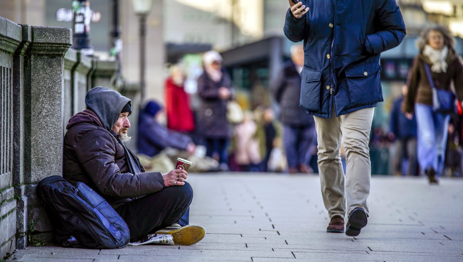 Ludzie przechodzą obojętnie obok bezdomnych w Hamburgu, Niemcy.