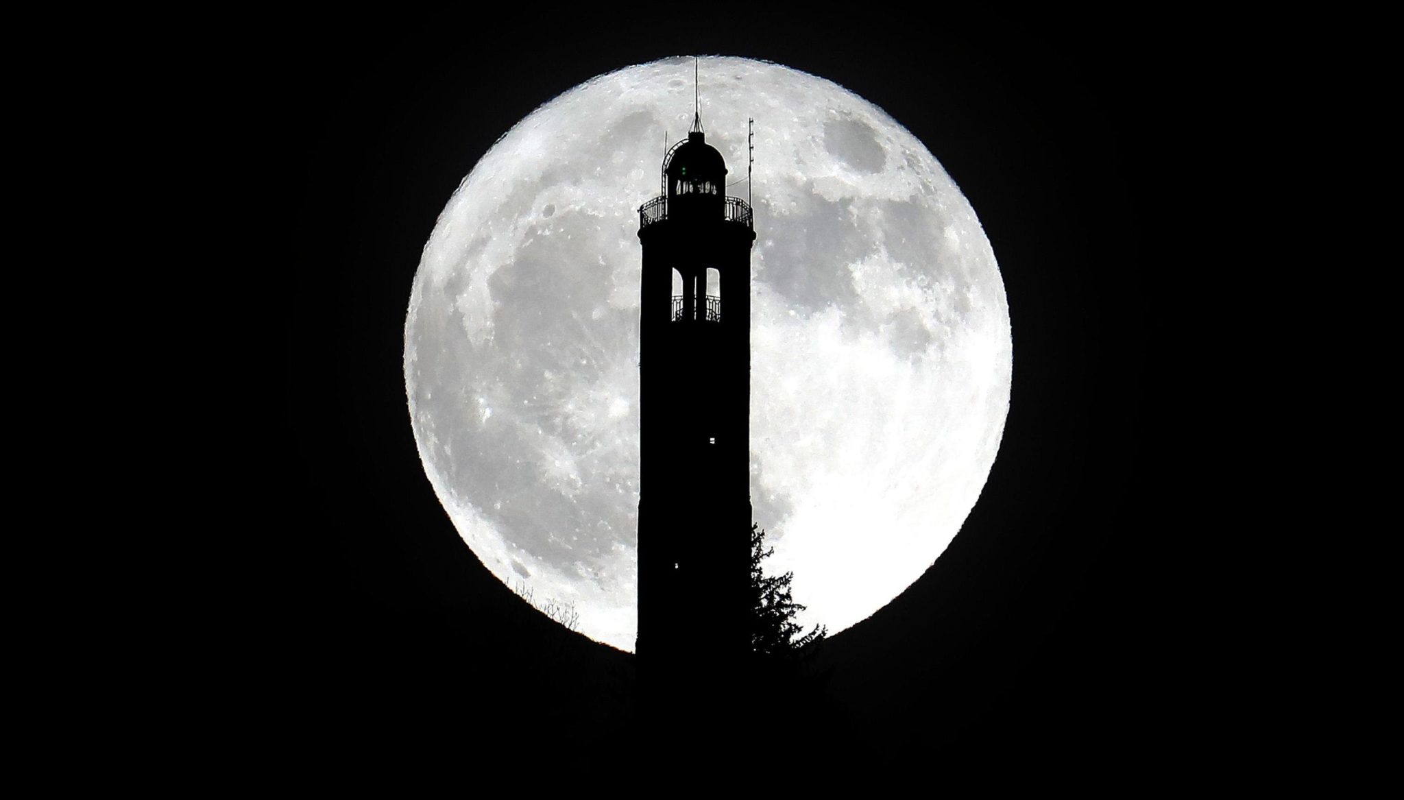Włochy: pełnia księżyca nad latarnią morską niedaleko Mediolanu, fot: Matteo Bazzi, PAP/EPA