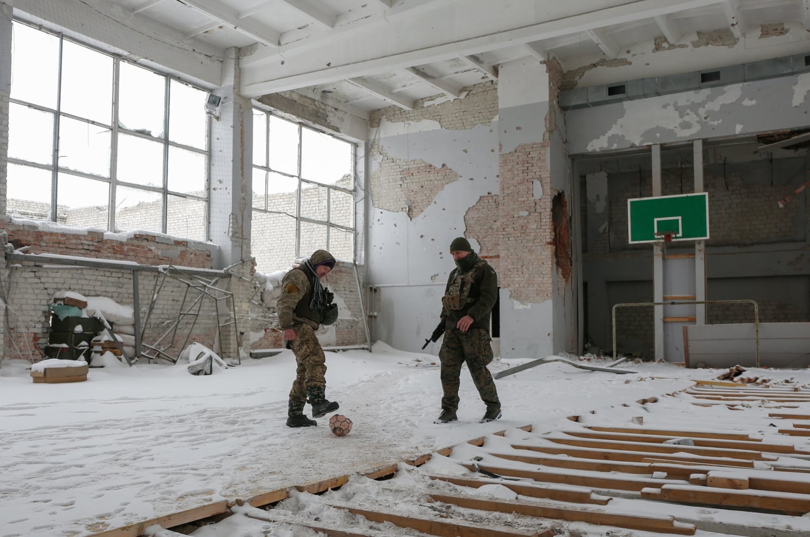 Ukraińscy żołnierze grają w piłkę w zniszczonym budynku szkoły niedaleko frontu, Ukraina.