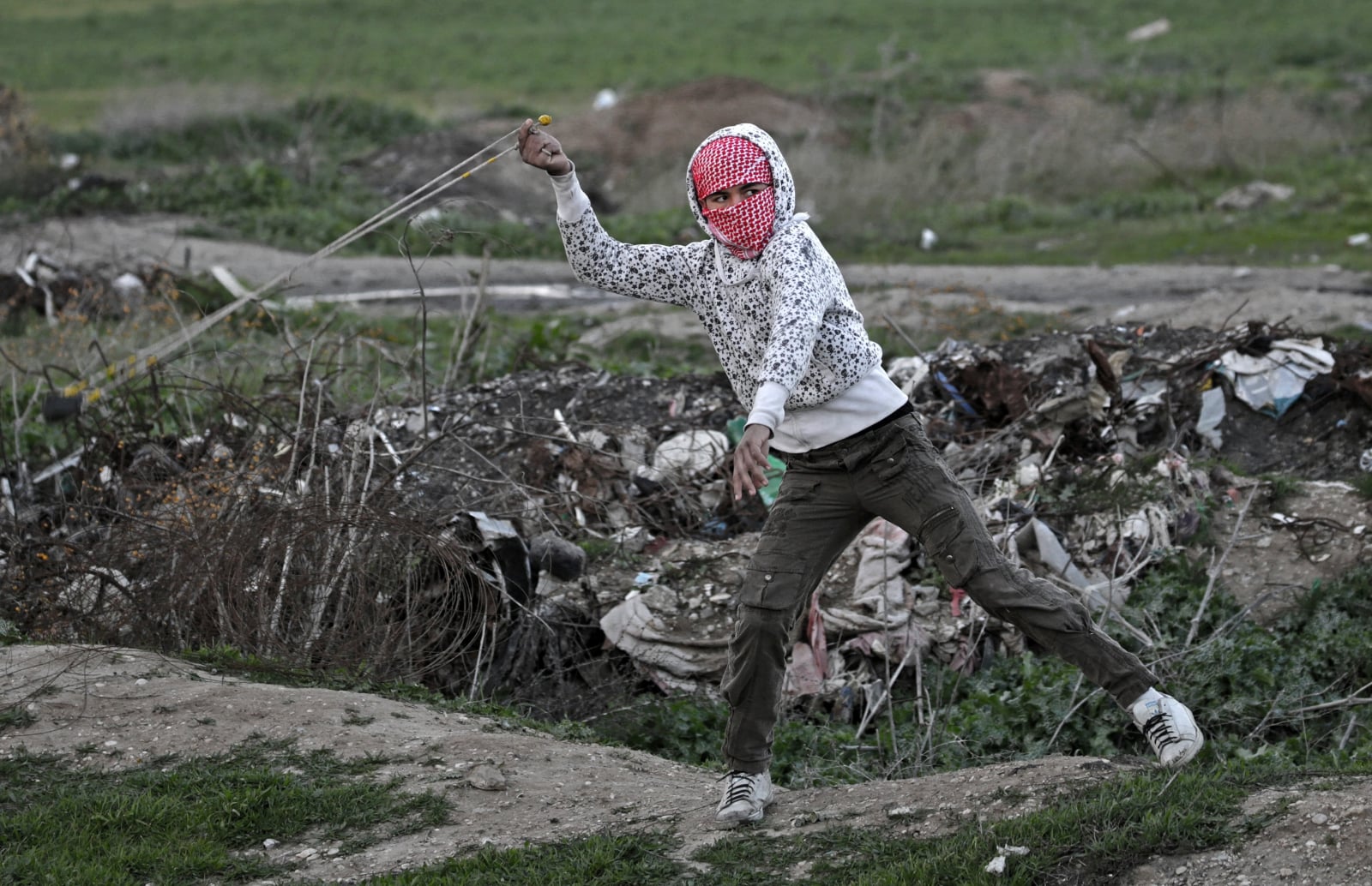Palestyńczyk rzuca kamieniami w izraelskich żołnierzy, Strefa Gazy.