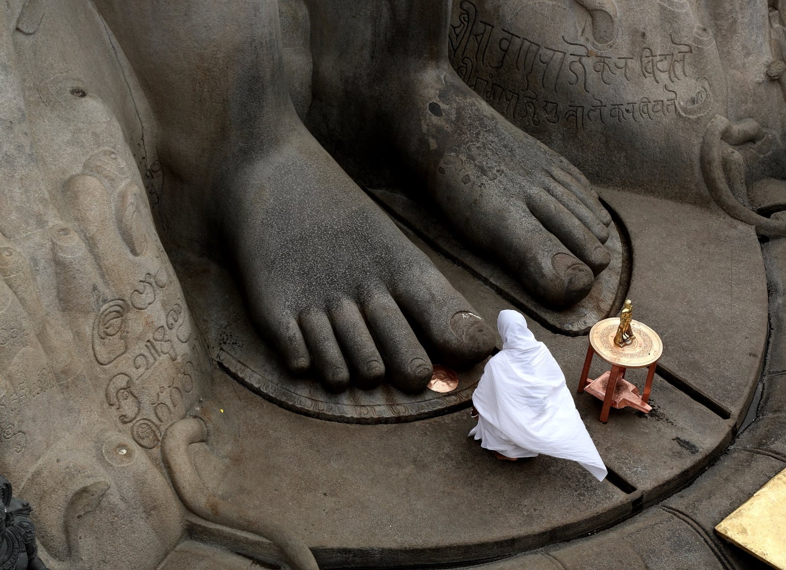 epaselect epa06503111 A Jain nun offers prayers at vindyagiri hills by touching the feet of Lord Bhaubali statue on the occasion of the 88th 'Mahamastakabhisheka Mahotsav' ceremony in Shravanabelagola, India, 07 February 2018. The town of Shravanabelagola will attract millions of people from across the country for the head anointing ceremony of the 17-meter-tall statue of Lord Bahubali. The Jain ritual will run from 07 to 26 February and is only held once every 12 years.  EPA/JAGADEESH NV 
Dostawca: PAP/EPA.