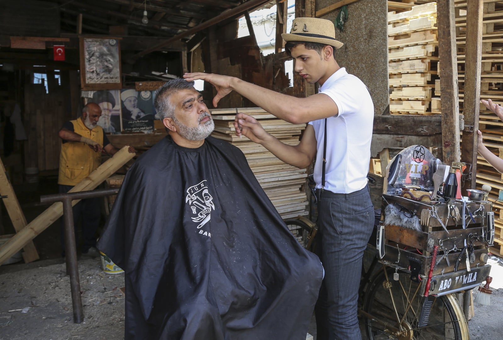 Libańczyk Mohammed Jahjah, który pracuje jako wędrowny barber, goli brodę swojemu klientowi na ulicy w obozie dla uchodźców w Bourj al-Barajneh, południowe przedmieścia Bejrutu, Liban, fot. EPA/NABIL MOUNZER  