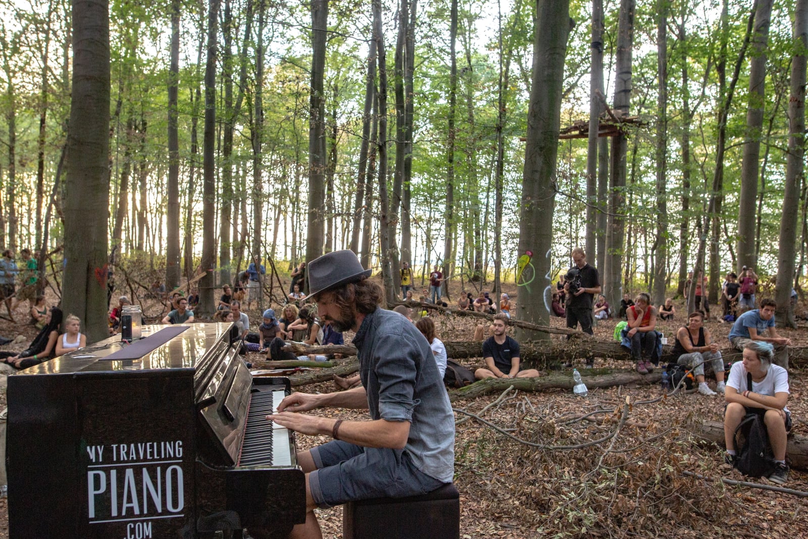Ludzie słuchający pianisty, który gra utwory żałobne na cześć zmarłego fotoreportera, który zginął w lesie Hambach, w Niemczech.