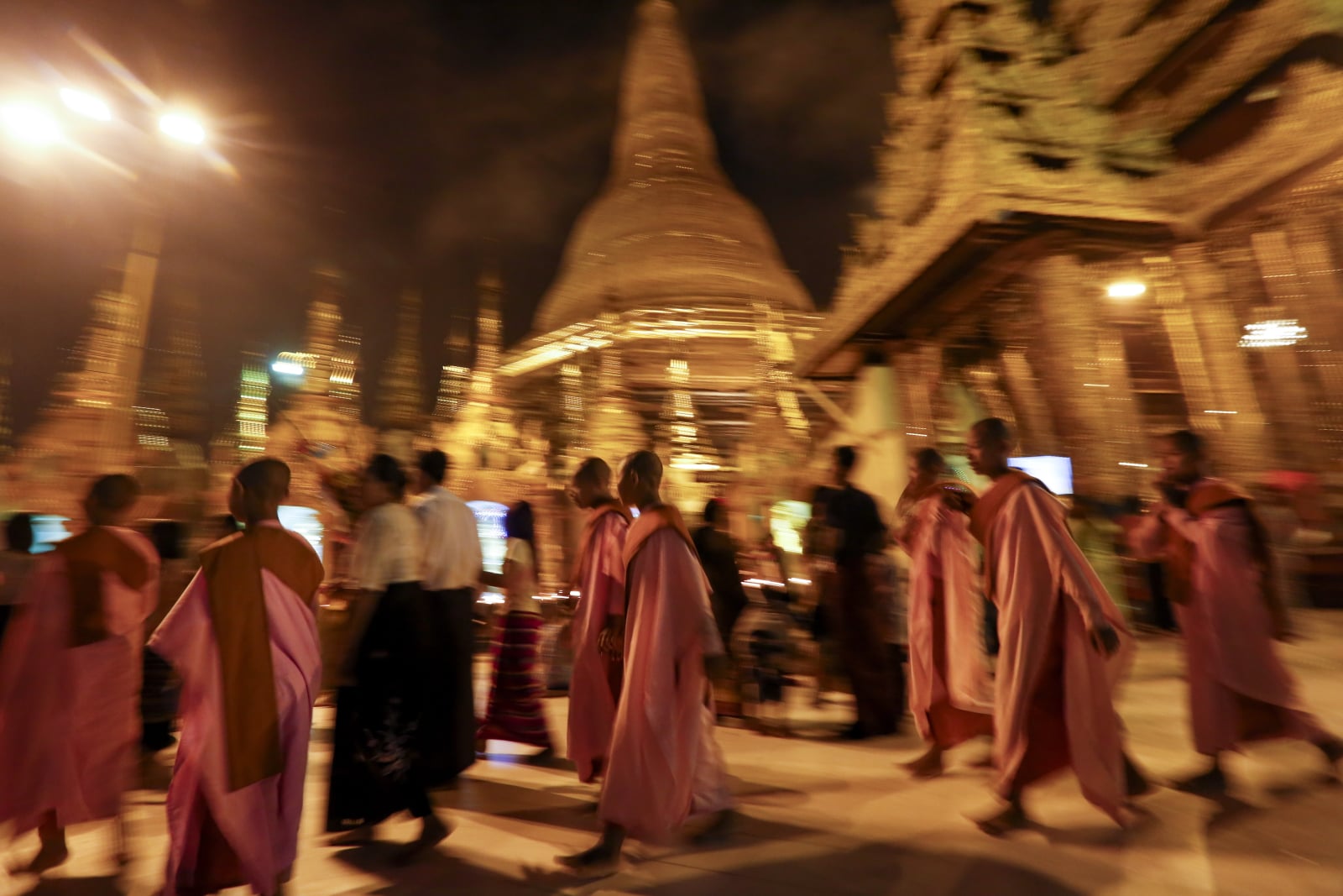 Buddyjskie zakonnice przechodzą obok posągu Shwedagon, podczas dnia księżycowego Yangon