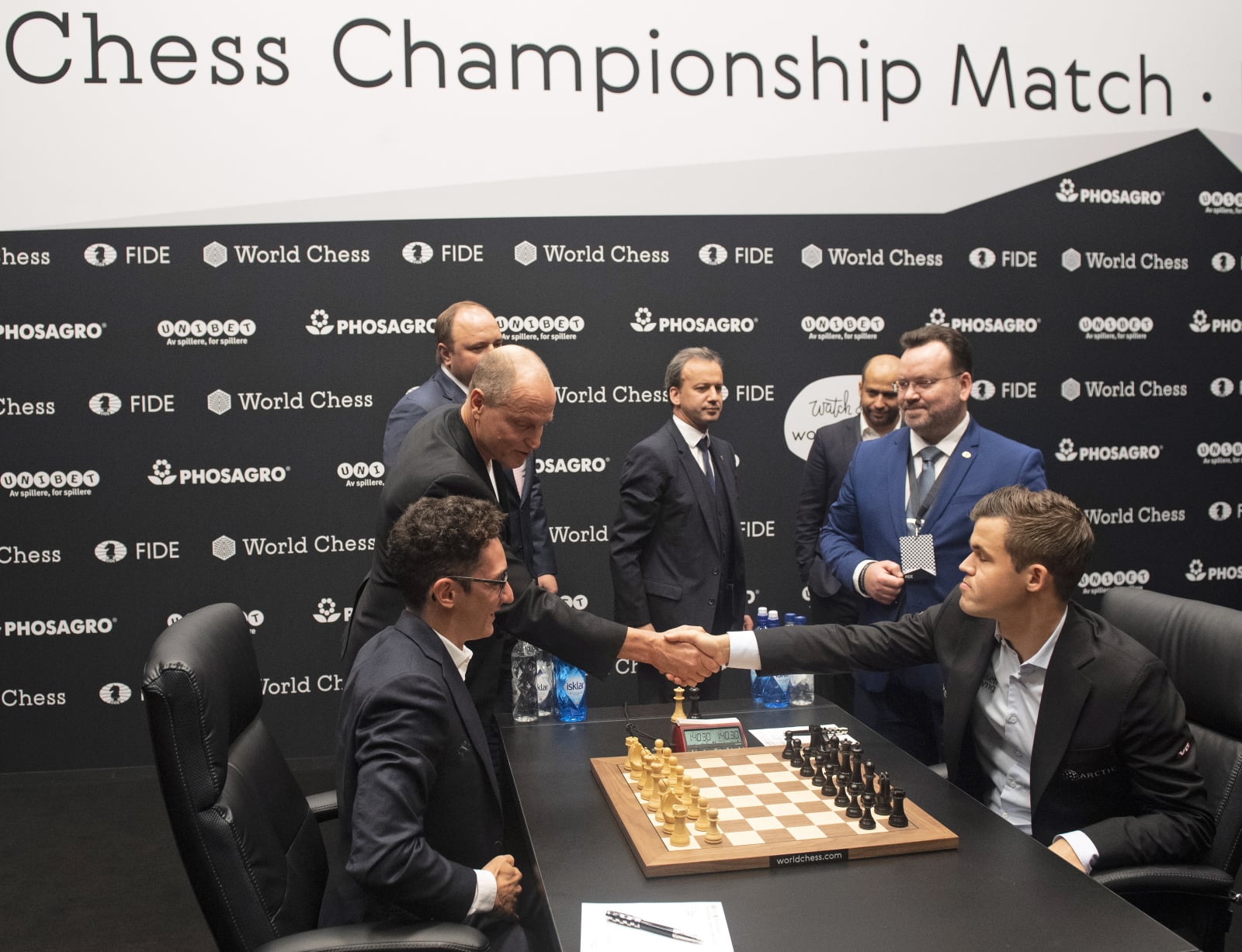 epa07154291 Norway's World Chess Champion Magnus Carlsen (R) shakes hand with US actor Woody Harrelson (2-L) after he accidentally knocked the White King before making the opening gambit move for US challenger Fabiano Caruana (seated L) of their Round One game during the World Chess Championship 2018, in London, Britain, 09 November 2018. Others are not identified  EPA/FACUNDO ARRIZABALAGA