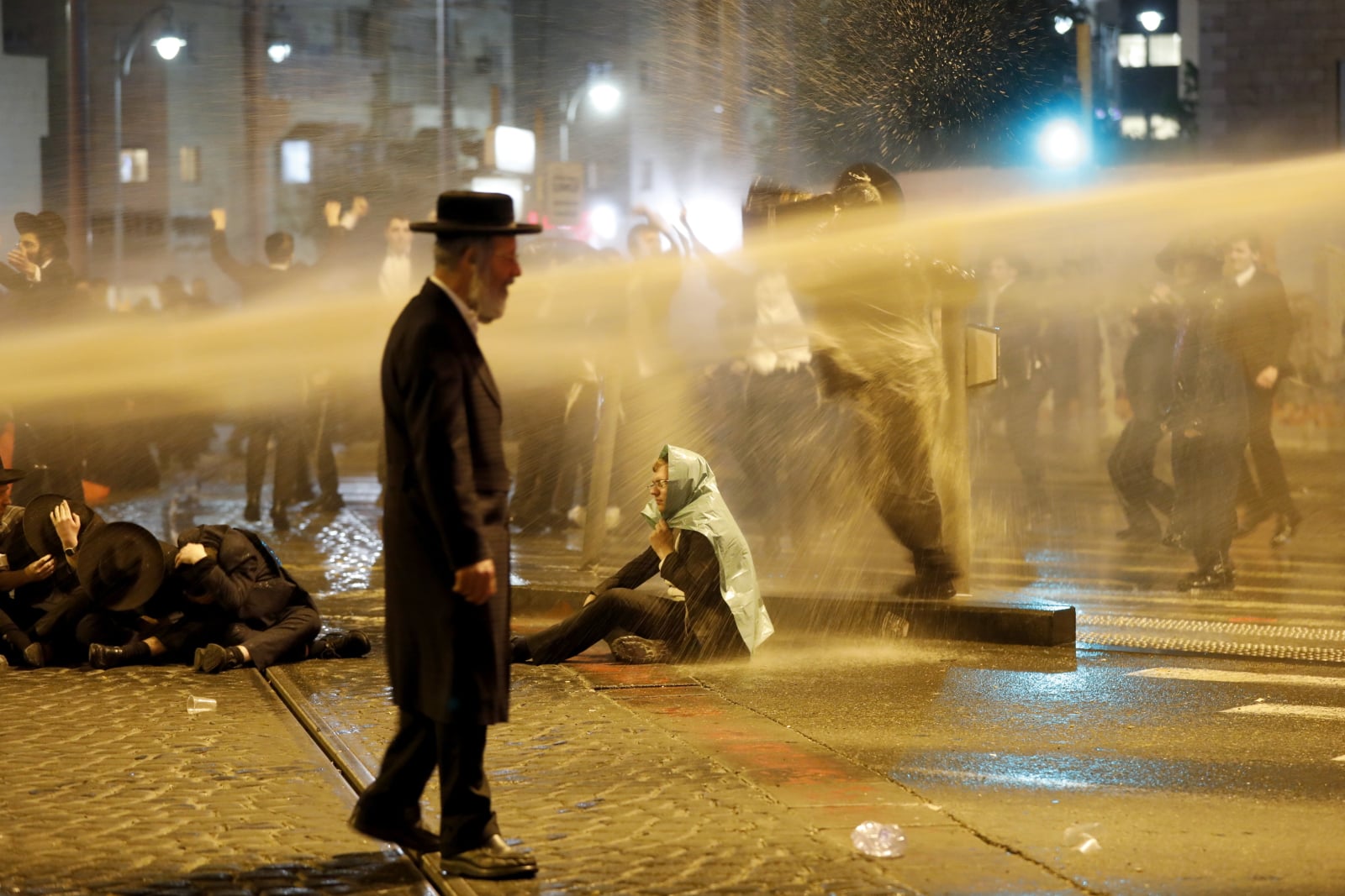 Policja używa armat wodnych, aby rozpędzić ultraortodoksyjnych żydowskich demonstrantów, którzy blokują tor Lekkiej Kolei podczas protestu przeciwko rekrutacji armii w centralnej Jerozolimie, Izrael