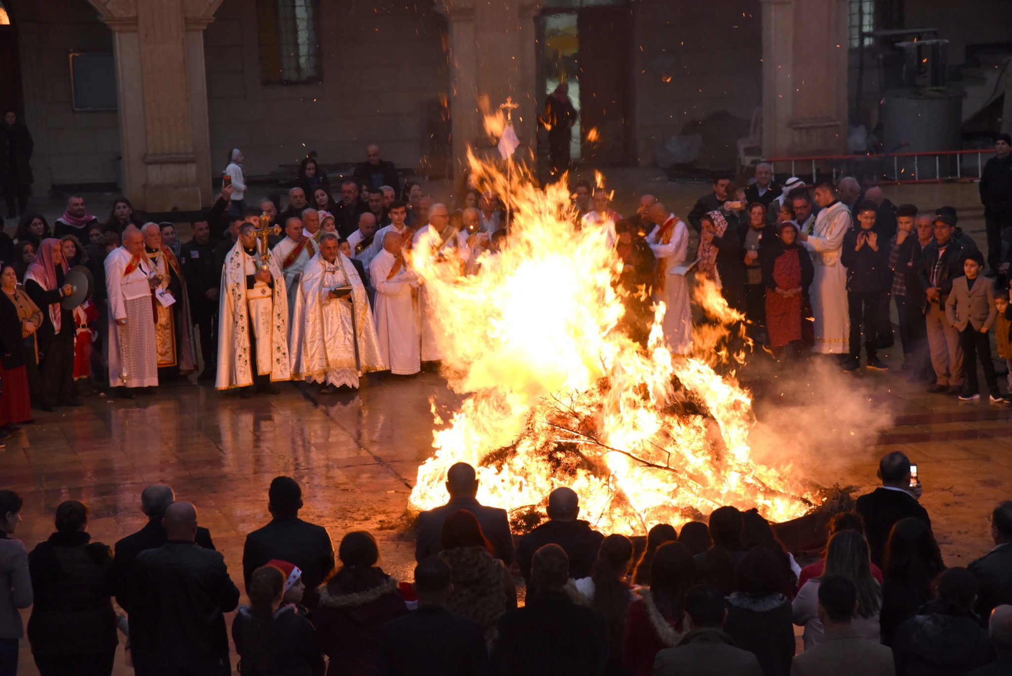 Iraccy chrześcijanie gromadzą się wokół ognia podczas procesji wigilijnej w kościele al-Tahira al-Kubra w asyryjskim miasteczku Qaraqosh, około 13 km na wschód od Mosulu, fot. Ammar Salih, PAP/EPA 
