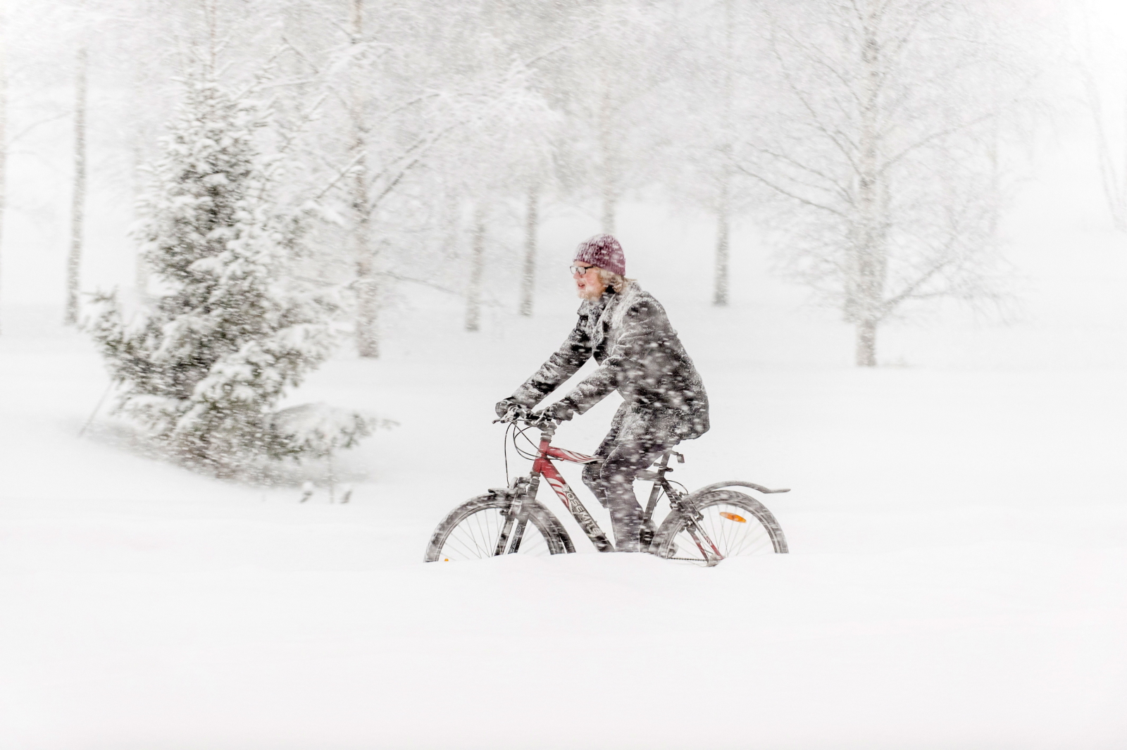 Mężczyzna jedzie na rowerze w trakcie śnieżycy, Vantaa, Finlandia. Fot. PAP/EPA/MARKKU OJALA