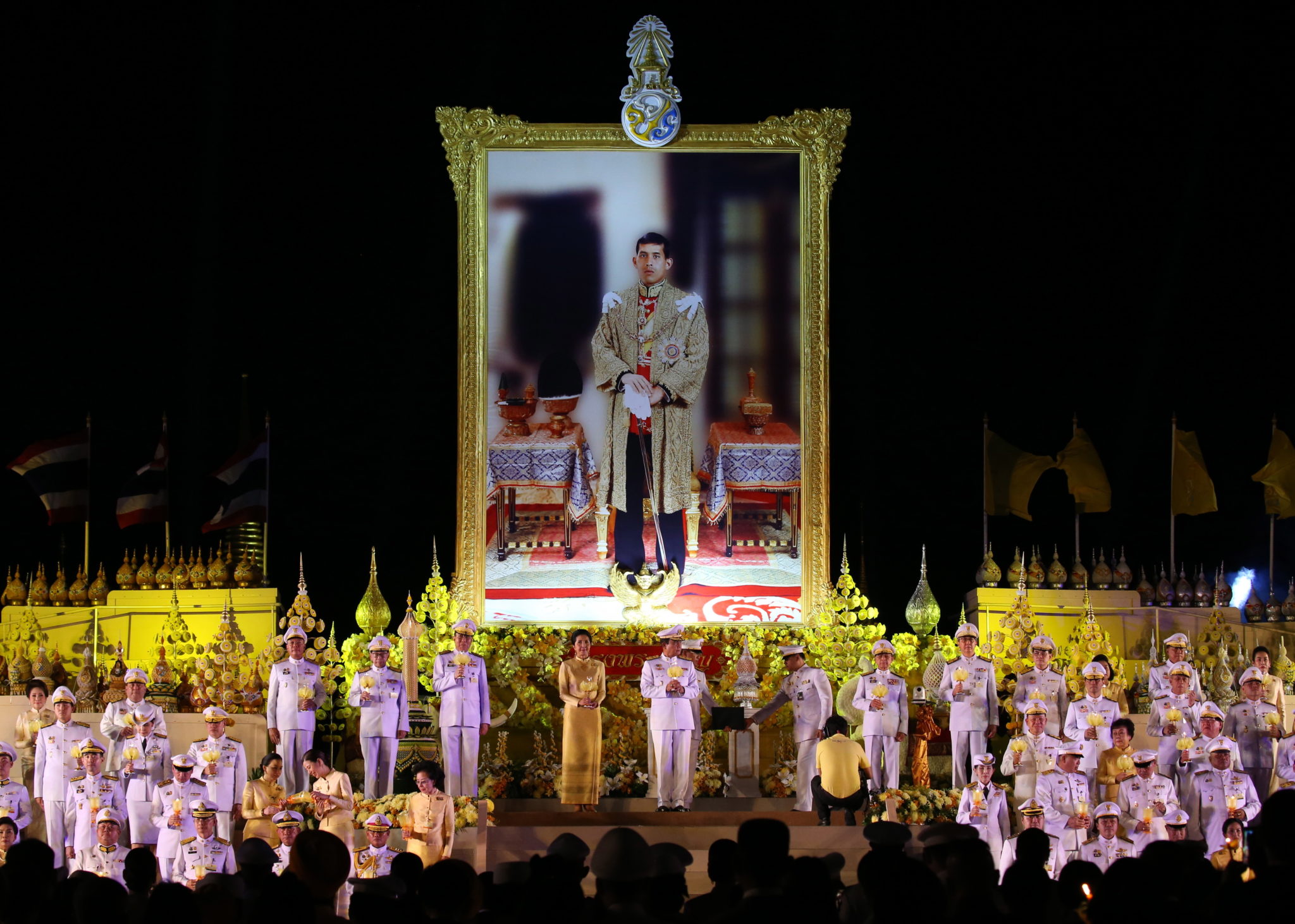 Tajlandia: Premier Prayut Chan-o-cha i jego żona zapalają świecę przed ogromnym portretem królaTajlandii  podczas ceremonii upamiętniającej jego 67. urodziny w Sanam Luang w Bangkoku. Fot. NARONG SANGNAK, PAP/EPA.