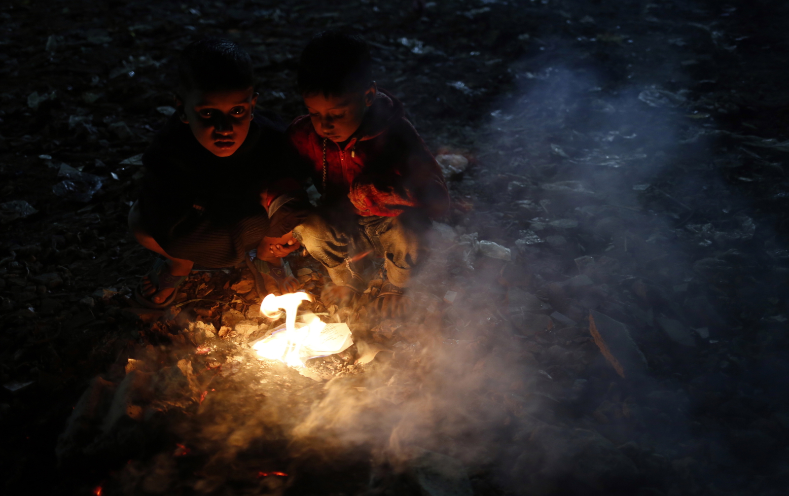 Dzieci na wysypisku śmieci w Bangladeszu próbują się ogrzać w zimna noc  EPA/MONIRUL ALAM 
