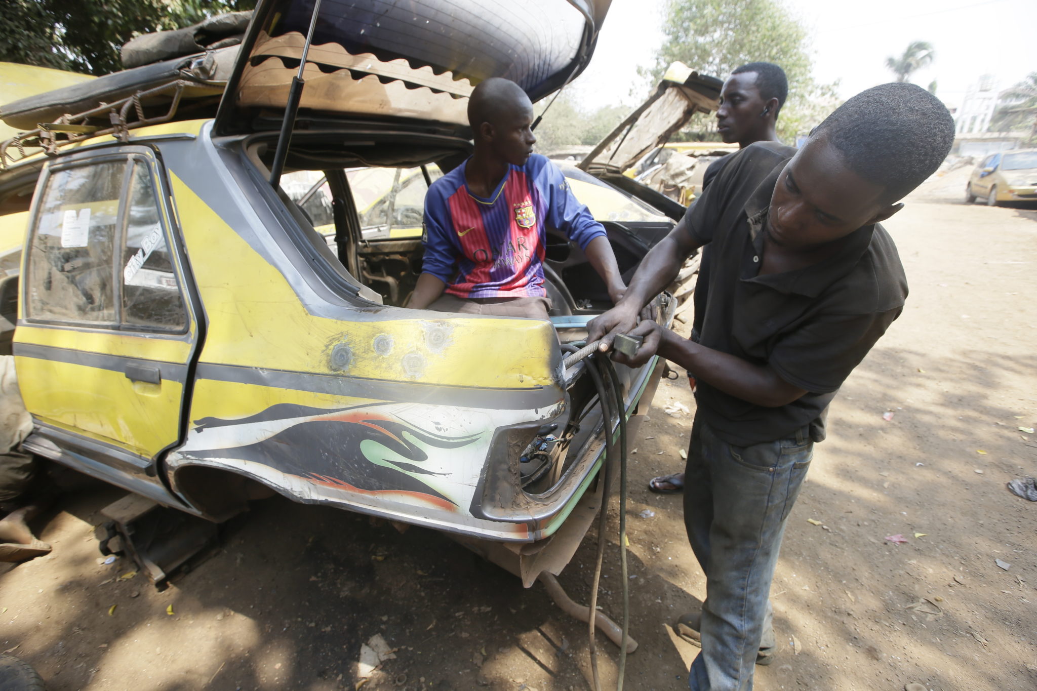 Gwinea: mechanik samochodowy wykonuje naprawy karoserii pojazdu w garażu w Kaporo, fot EPA/AHMED JALLANZO 