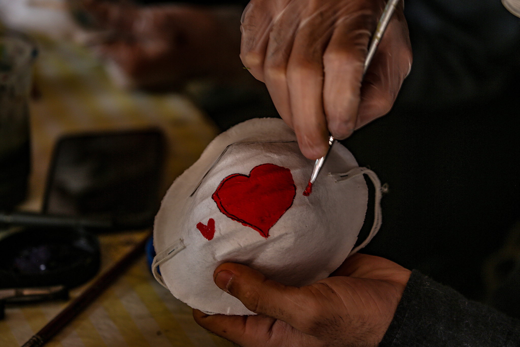 Palestyńscy artyści malują maseczki. Fot. EPA/MOHAMMED SABER 