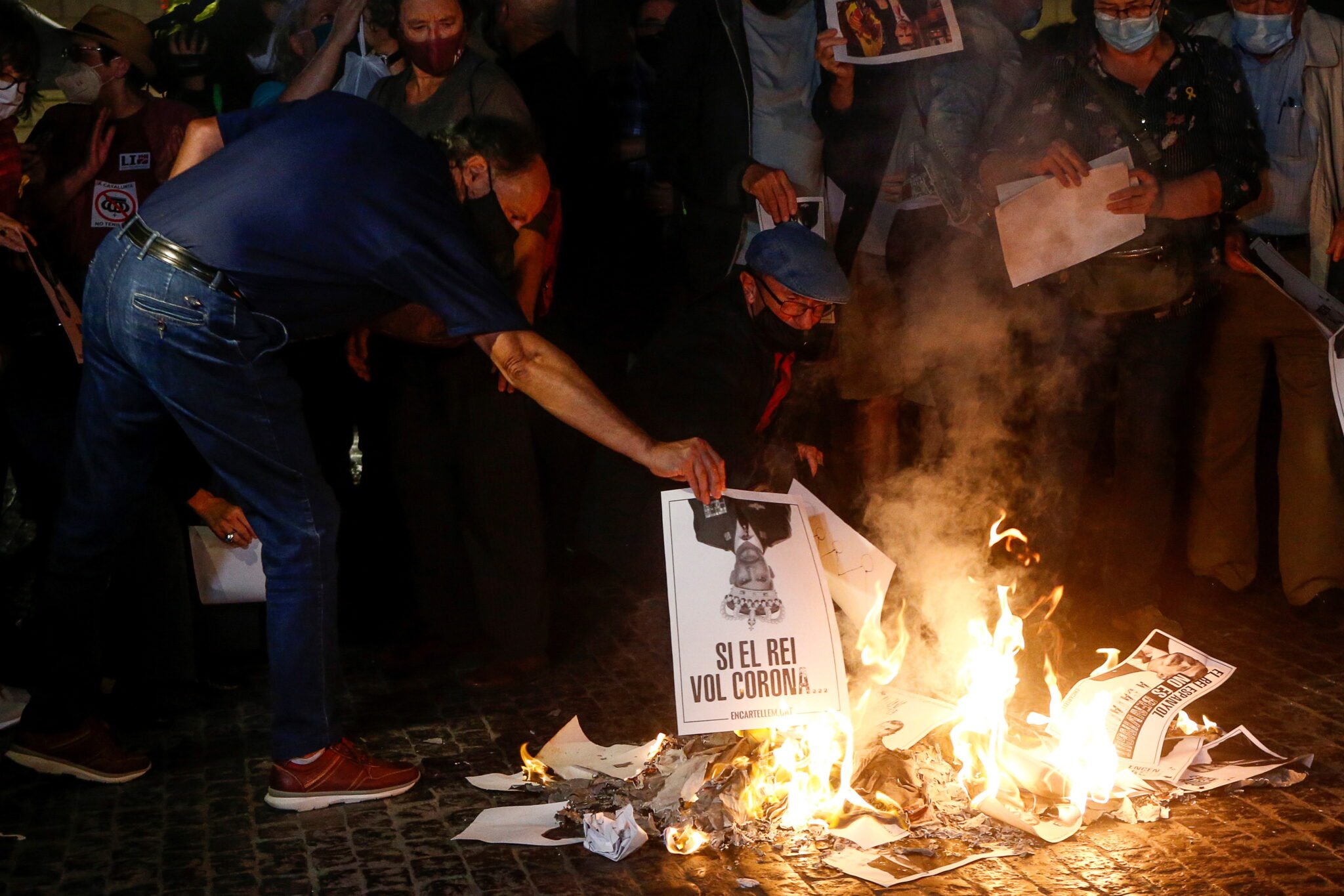 Ludzie palą zdjęcia hiszpańskiego króla Filipa VI podczas protestu z okazji jego wizyty w Barcelonie, Katalonii, fot. EPA / QUIQUE GARCIA 