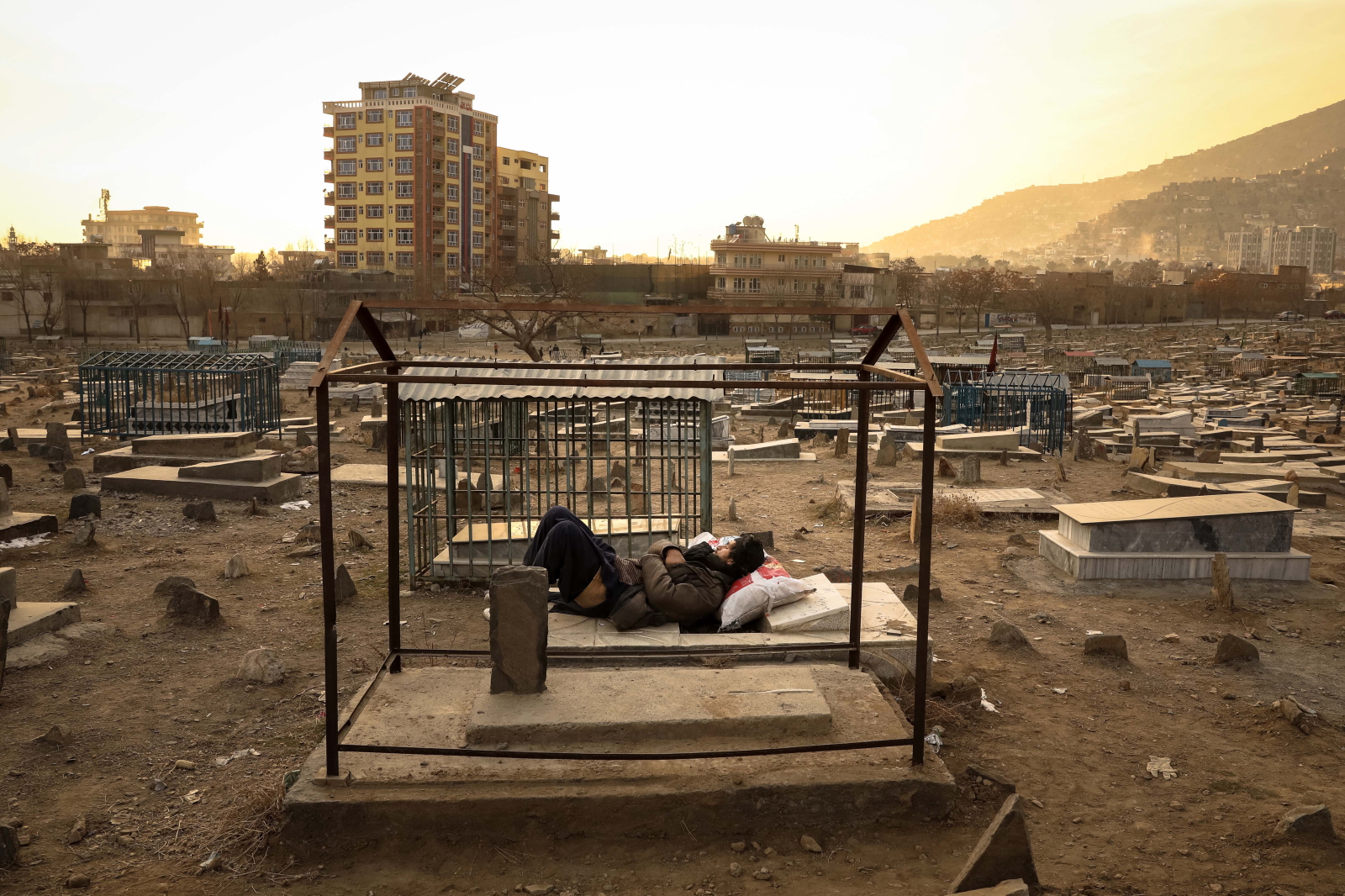 Człowiek śpiący na grobie w Afganistanie Fot. PAP/EPA/HEDAYATULLAH AMID