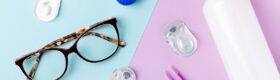 Contact lens kit with bottle of lens solution, case, tweezer on multicolor background, copy space, top view