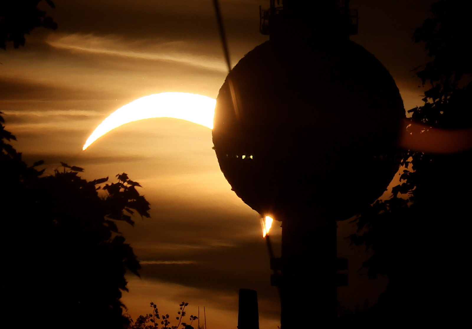 epa13164376 A part of the Sun obscured by the Moon during a partial solar eclipse is seen behind the TV tower in Berlin, Germany, 12 August 2026. A total solar eclipse will sweep across parts of Europe and the North Atlantic on 12 August, with the path of totality moving through Greenland, Iceland, Spain, and a small section of northeastern Portugal, while surrounding areas across Europe experience a partial solar eclipse, according to the European Space Agency (ESA). EPA/HANNIBAL HANSCHKE Dostawca: PAP/EPA.